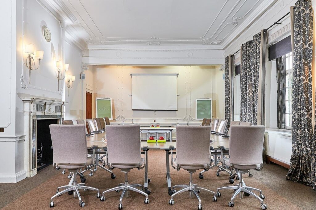 A meeting room in Milton with pink chairs in front of a whiteboard, creating a modern and inviting atmosphere.